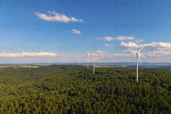 Wind turbines over a thick forest under a clear blue sky with some clouds, near Schorndorf, Rems-Murr-Kreis, Baden-Württemberg, Germany