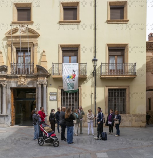 Tour guide and group of people outside museum of sacred art building, cathedral square, Teruel, Aragon, Spain