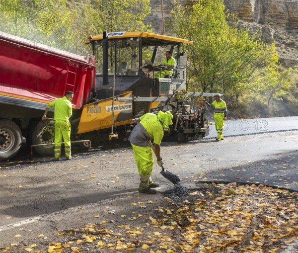 Asphalt road construction team of workers resurfacing tarmac in rural area, near Albarracin, Teruel province, Aragon, Spain