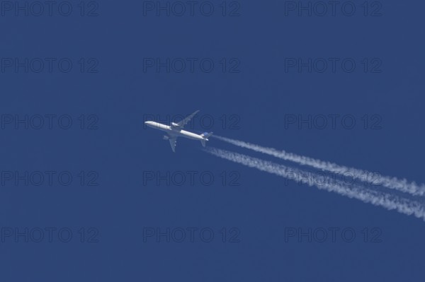 Boeing jet passenger aircraft of United airways airlines flying in a blue sky with contrails or vapour trails behind, England, United Kingdom