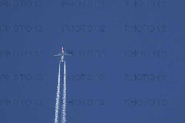 Boeing 737 jet passenger aircraft of Norwegian Air airlines flying in a blue sky with contrails or vapour trails behind, England, United Kingdom