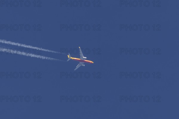 Boeing 767 jet cargo aircraft of DHL airlines flying in a blue sky with contrails or vapours trails behind, England, United Kingdom