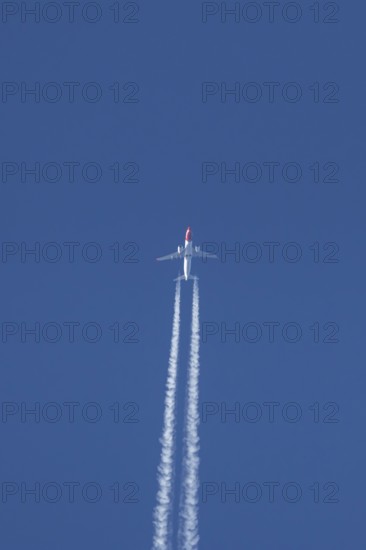 Boeing 737 jet passenger aircraft of Norwegian Air airlines flying in a blue sky with contrails or vapour trails behind, England, United Kingdom
