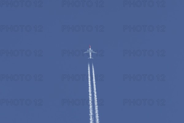 Boeing 737 jet passenger aircraft of Norwegian Air airlines flying in a blue sky with contrails or vapour trails behind, England, United Kingdom