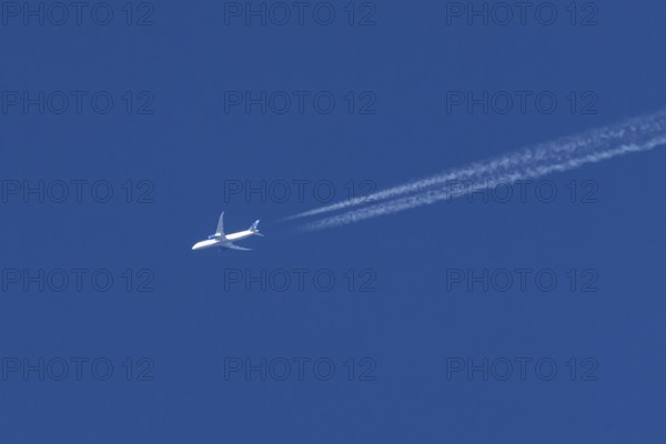 Boeing jet passenger aircraft of United airways airlines flying in a blue sky with contrails or vapour trails behind, England, United Kingdom