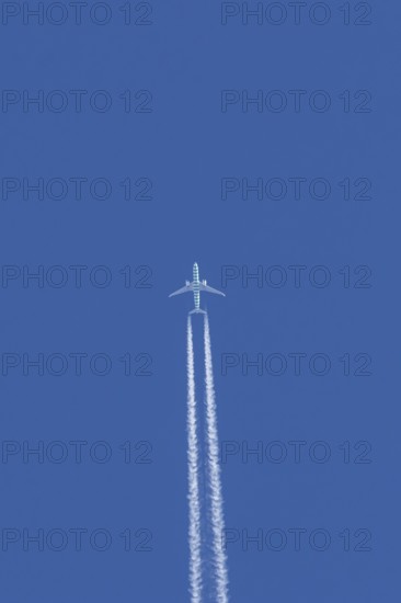 Boeing jet passenger aircraft flying in a blue sky with contrails or vapour trails behind, England, United Kingdom
