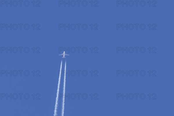 Airbus jet passenger aircraft of Easyjet airlines flying in a blue sky with contrails or vapour trails behind, England, United Kingdom