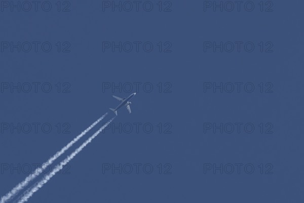 Boeing 737 jet passenger aircraft of Ryanair airlines flying in a blue sky with contrails or vapour trails behind, England, United Kingdom