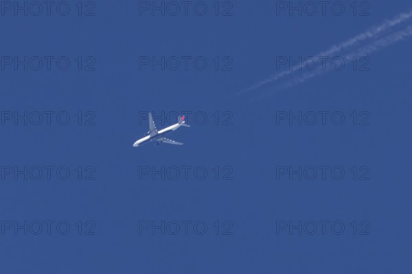Boeing jet passenger aircraft of Delta airways airlines flying in a blue sky with contrails or vapour trails behind, England, United Kingdom