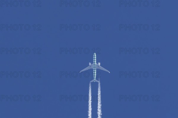 Boeing jet passenger aircraft flying in a blue sky with contrails or vapour trails behind, England, United Kingdom