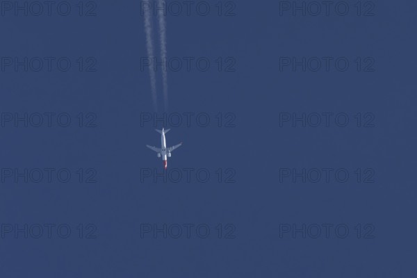 Boeing 737 jet passenger aircraft of Norwegian Air airlines flying in a blue sky with contrails or vapour trails behind, England, United Kingdom