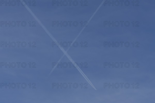 Aircraft contrails or vapour trails crossing in a blue sky, England, United Kingdom