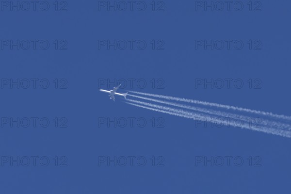 Airbus A340 jet passenger aircraft of Lufthansa airlines flying in a blue sky with contrails or vapour trails behind, England, United Kingdom