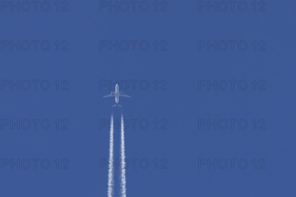 Airbus jet passenger aircraft of Kuwait airways flying in a blue sky with contrails or vapour trails behind, England, United Kingdom