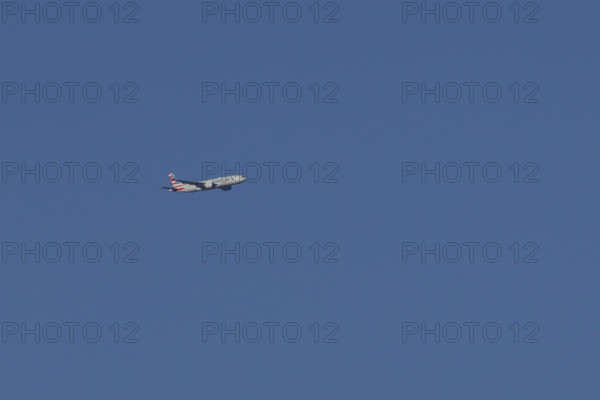 Boeing 777 jet passenger aircraft of American airlines flying in a blue sky, England, United Kingdom