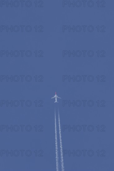 Boeing 737 jet passenger aircraft of Norwegian Air airlines flying in a blue sky with contrails or vapour trails behind, England, United Kingdom