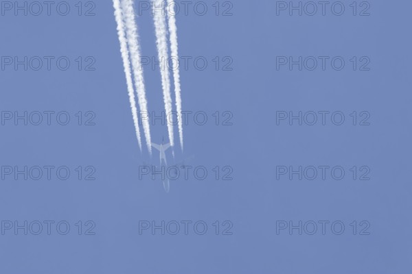 Boeing 747 jumbo jet passenger aircraft of Lufthansa airlines flying in a blue sky with contrails or vapour trails behind, England, United Kingdom