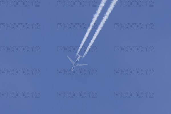 Jet passenger aircraft of Delta airlines flying in a blue sky with contrails or vapour trails behind, England, United Kingdom