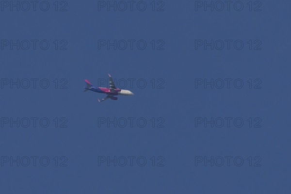 Airbus jet passenger aircraft of Wizz Air airlines flying in a blue sky, England, United Kingdom