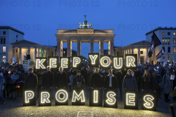 Participants hold glowing letters with the words Keep Your Promises at the international climate demo under the slogan Fight for 1.5 at the Brandenburg Gate in Berlin on 14.11.2025. The demonstration takes place on the occasion of the COP30 World Climate Conference in Belém, Brazil, and to mark 10 years of the Paris Climate Agreement