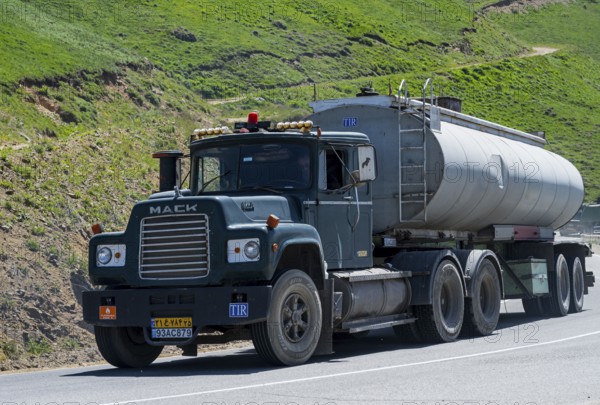 A green truck with a tank trailer is driving on a mountain road, Mack truck with Iranian license plate on M2 near Meghri Pass, Tashtun Pass, Syunik province, Armenia
