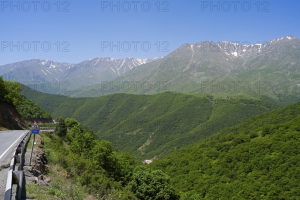 A winding mountain road snakes through green hills with mountains in the background, landscape on M2 near Meghri Pass, Tashtun Pass, Syunik Province, Armenia