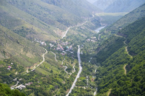 View of a village in the valley surrounded by green hills and a river, with winding roads through the countryside, view of Lernadzor, surrounded by the mountains of the Zangesur Range, Sangesur, Syunik province, Caucasus, Armenia