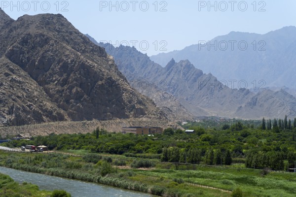 A green landscape with a river and mountains in the background, view of Iran, Aras River near Meghri, Syunik Province, Armenia
