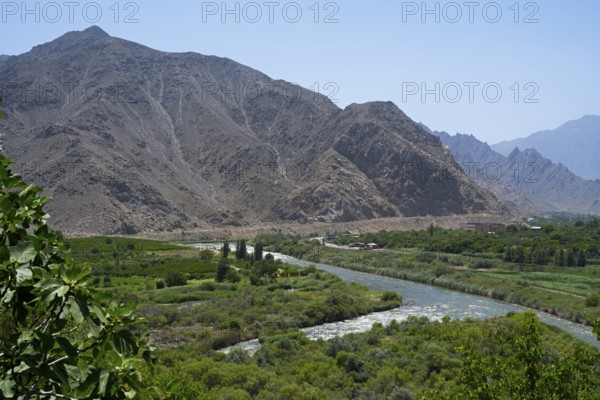 A river crosses a green valley surrounded by rugged mountains, view of Iran, Aras river near Meghri, Syunik province, Armenia
