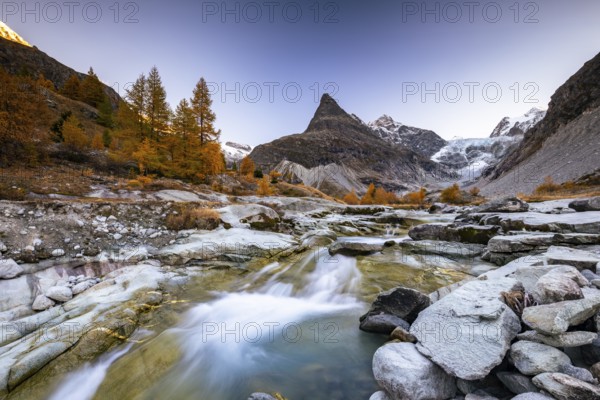 Mountain stream with autumnal larches and mountain views, Mont Mine, Ferpecle glacier, Val d'Herens, Canton of Valais, Switzerland