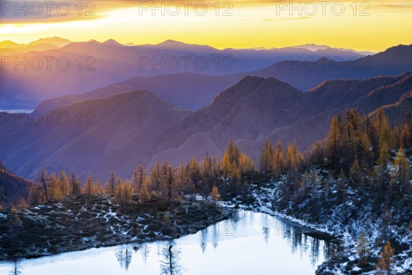 Laghetto dei Saléi mountain lake with autumnal larches (Larix) at sunrise, Onsernone Valley, Canton of Tessin, Switzerland