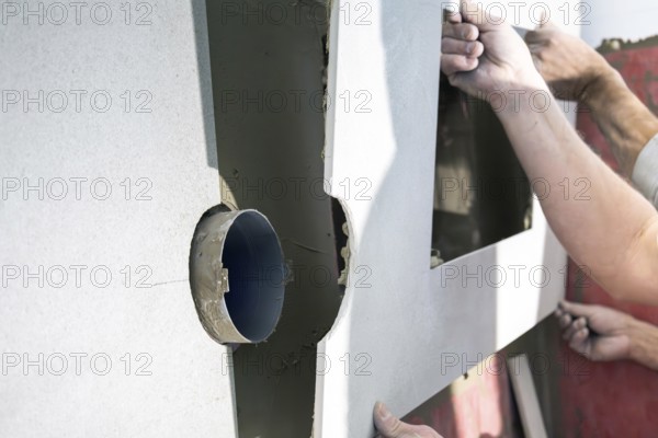 Tilers install wall tiles in a new bathroom