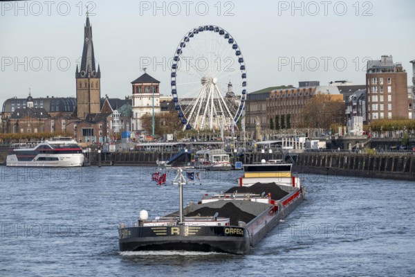 Dutch cargo ship Orfeo, brings power plant coal from the Netherlands to Mannheim, here on the Rhine near Düsseldorf, old town backdrop with giant wheel, North Rhine-Westphalia, Germany