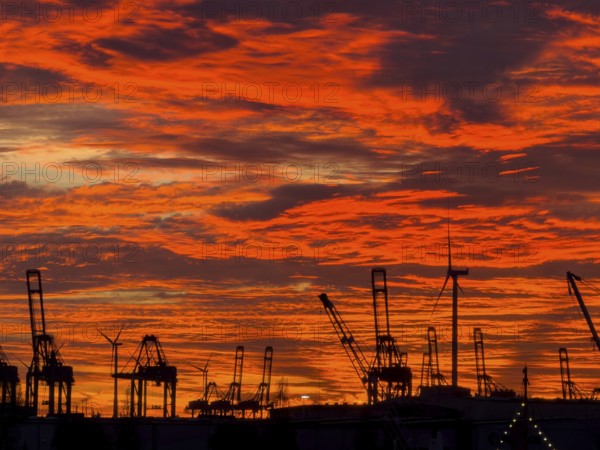 Dramatic sunset sky at Hamburg's Landungsbrücken with silhouetted cranes and wind turbines in the foreground, Hamburg, Germany