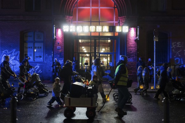 Participants with lanterns and strollers parade in front of the Arminiusmarkthalle during the lantern parade for Marting Day in Berlin Moabit on 11.11.2025