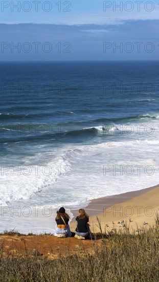 Tourists watch the waves of the Atlantic on the rocky plateau of Sito, also known as Forte São Miguel, a surfing paradise with monster waves in the months of November to February, Nazaré, Portugal