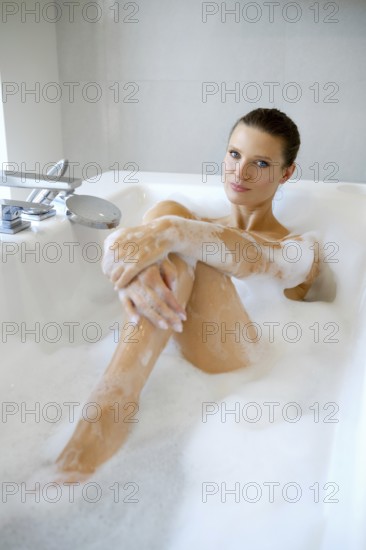A woman enjoys a soothing bubble bath, surrounded by soft lighting in a contemporary bathroom