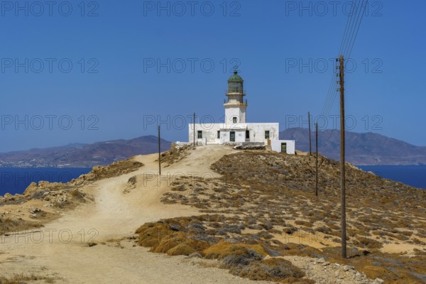 Mykonos, Cyclades, Greece - The Armenistis lighthouse in the north of the island is a landmark and a popular destination for tourists. In the back is the island of Tinos