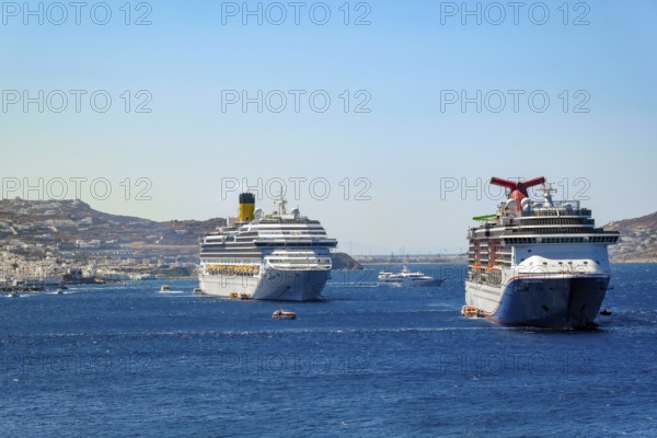Mykonos, Cyclades, Greece - cruise ships CARNIVAL MIRACLE and COSTA FORTUNA are located in the bay off Mykonos City. Old town with windmills. Cruise ships bring tourists to shore