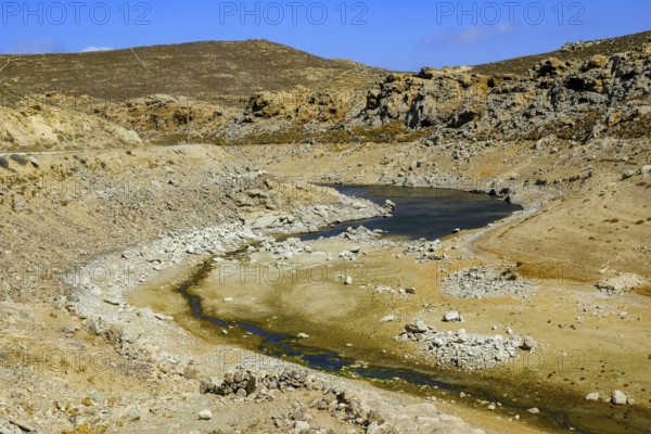 Mykonos, Cyclades, Greece - Dry Fokos Reservoir near Ano Mera. The Mykonos Municipal Water Supply and Sewage Management Company has two dams, Marathi Reservoir and Fokos Reservoir, to supply water to the island. Due to the prolonged drought, both are almost empty and are not being used