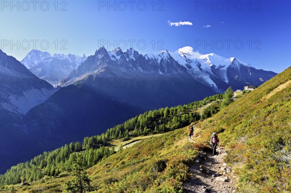 Female hiker on a hiking trail with the La Flégère cable car mountain station and the snow-covered Mont Blanc massif, Chamonix-Mont-Blanc, Haute-Savoie, France