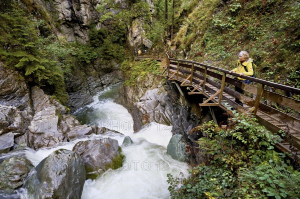 Female hiker standing on wooden walkway, Diosaz mountain river in the gorge, Gorges de la Diosaz, Les Houches, Chamonix-Mont-Blanc, Haute-Savoie, France