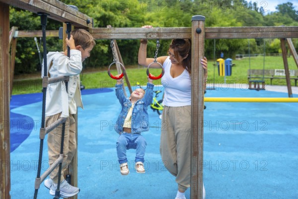Mother watching children playing joyfully on monkey bars at the playground, fostering family bonding and encouraging outdoor fun during a sunny summer day filled with laughter