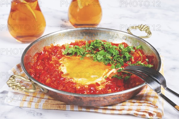 Traditional Turkish dish, scrambled eggs with tomatoes, Menemen, with herbs, in a frying pan, close-up, no people