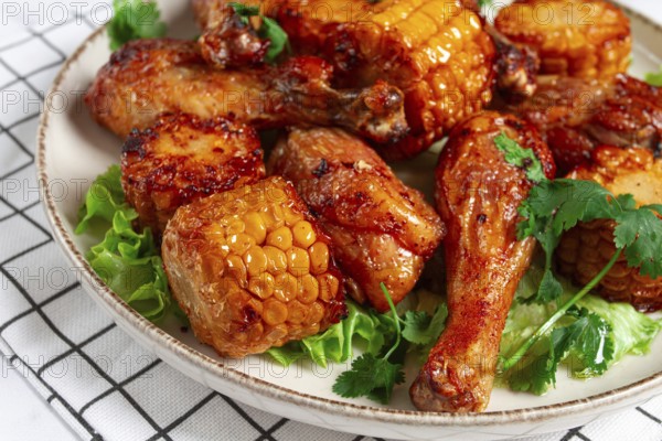 Fried chicken drumsticks, Mexican style, with corn, on a plate, close-up