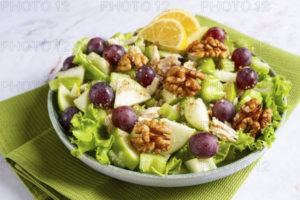Fresh Waldorf salad, celery stalk with chicken, apple and walnuts, grapes, herbs, homemade, without people