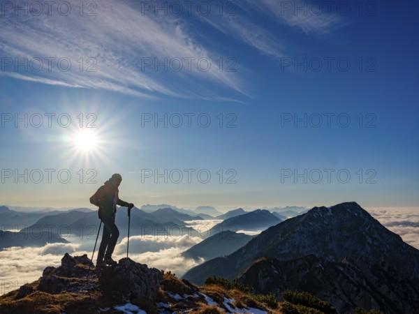 Mountaineer looking at blue-colored silhouette of mountains, fog in the valley, Hochstaufen, Chiemgau Alps, Upper Bavaria, Bavaria, Germany