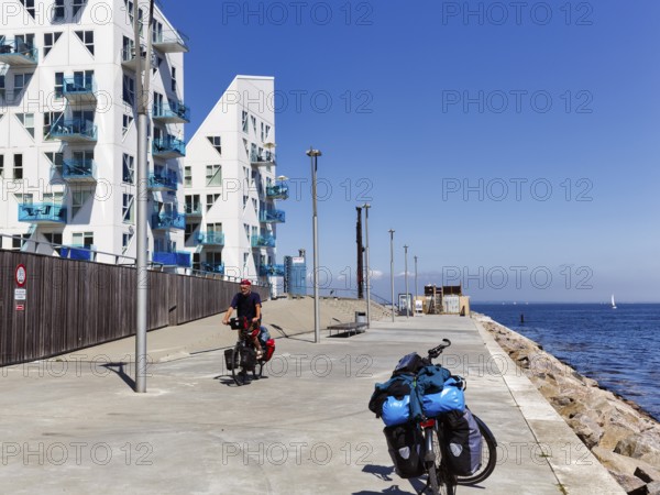 Cyclists, e-bikes with luggage bags, bike tour, pyramid-shaped buildings, sunny summer weather, Isbjerget residential district, iceberg, modern architecture overlooking the sea, Aarhus, Jutland, Denmark
