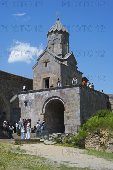 Popular chapel with tower and group of visitors under blue sky, Tatev monastery, Armenian Apostolic Monastery, Syunik province, Syunik, Caucasus, Armenia