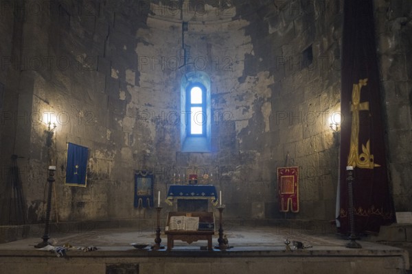 Illuminated church interior with altar, window and candles, filled with sacred atmosphere and decorations, Tatev monastery, Armenian Apostolic monastery, Syunik province, Caucasus, Armenia